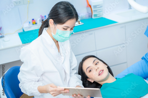 Dentist doctor hold tablet  advice patient girl in dental care clinic