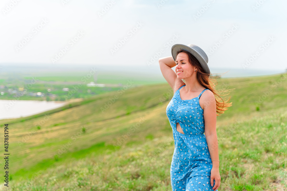 A cute woman in a dress walks through the meadows with a view of the picturesque landscape with hills A cute woman in a dress walks through the meadows with a view of the picturesque landscape with hills