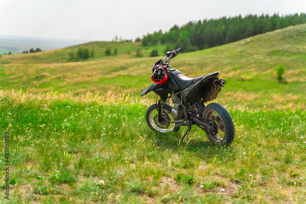 The motorcycle stands on a hill overlooking a beautiful landscape with green meadows. Togliatti, Russia - 20 May 2021: The motorcycle stands on a hill overlooking a beautiful landscape with green meadows. Togliatti, Russia - 20 May 2021: