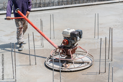 Worker use Power trowel machine on wet concrete.