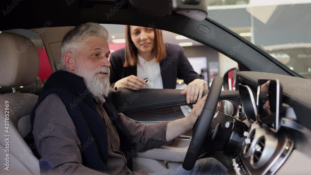 Senior man sitting in car consults with young woman dealer Spbi Senior man sitting in car consults with young woman dealer Spbi