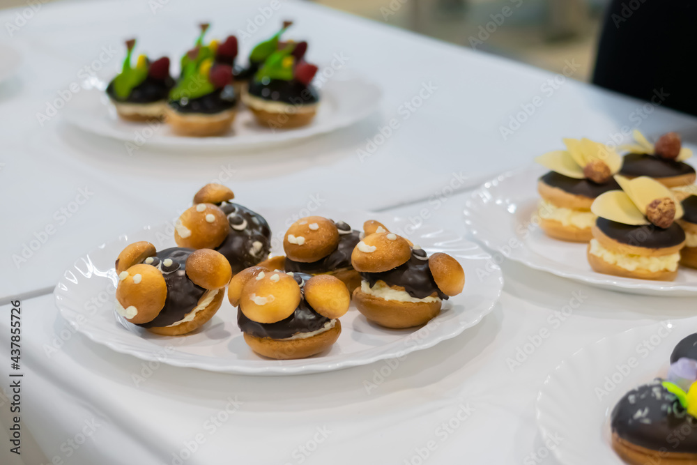 Assortment of delicious fresh shortcrust tart cakes with chocolate and sweet mushrooms on white plate for sale at restaurant, cafe. Dessert, culinary and confectionery concept Assortment of delicious fresh shortcrust tart cakes with chocolate and sweet mushrooms on white plate for sale at restaurant, cafe. Dessert, culinary and confectionery concept