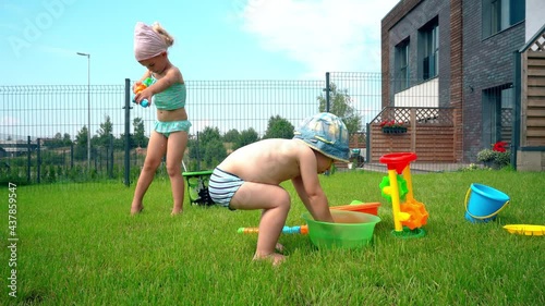 Caucasian brother and sister in swimsuits play with plastic toys watering can