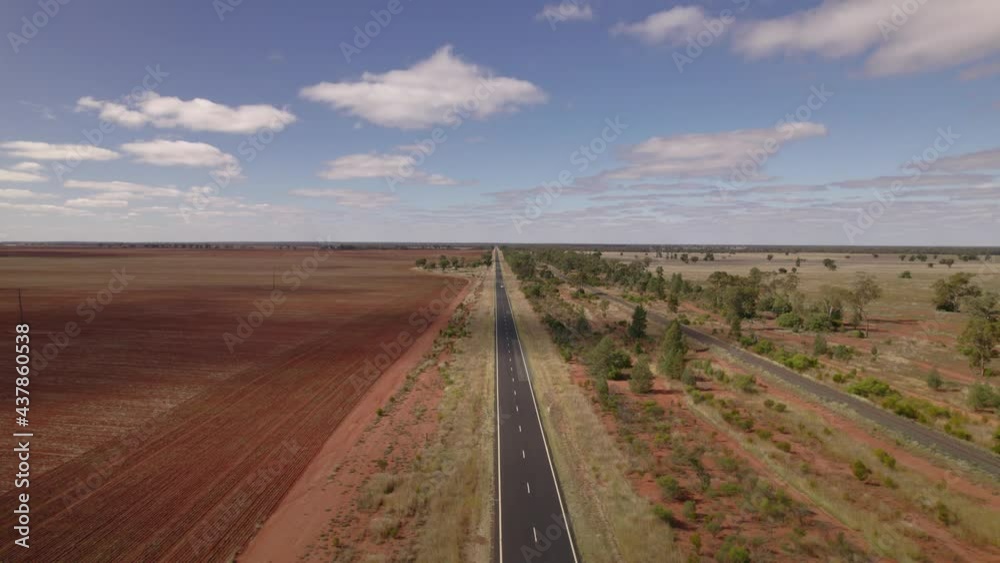 A lone vehicle travels down a highway in Australia's outback from an endless horizon A lone vehicle travels down a highway in Australia's outback from an endless horizon