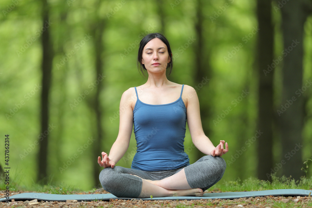 Asian woman doing yoga lotus pose in a forest