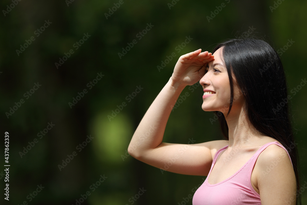 Happy woman watching protecting from sun in a park
