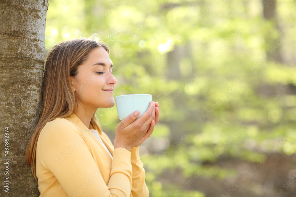 Woman smelling coffee in a forest or park Woman smelling coffee in a forest or park