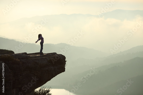 Woman screaming in the top of a cliff in the mountain photo