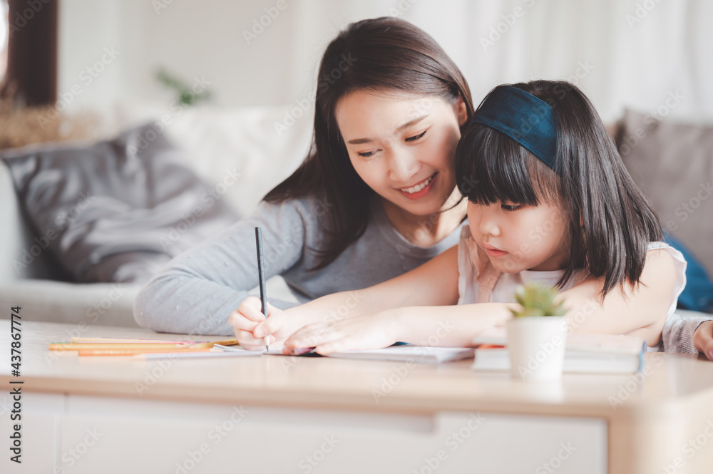 Happy Asian family mother and daughter study or drawing together at home in living room Happy Asian family mother and daughter study or drawing together at home in living room