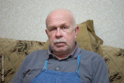 Indoor portrait of a Caucasian senior man looking with pacification while sitting on a sofa.