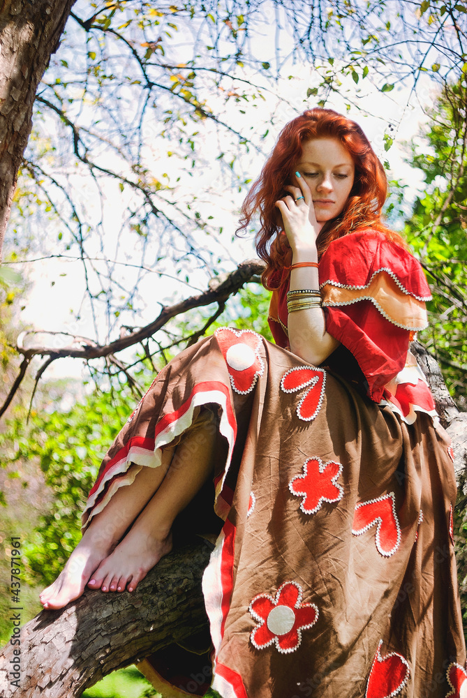 Stylish girl with freckles and red hair in red long dress dancing at green wild forest on nature. Portrait of boho woman posing in summer countryside. Happy lifestyle. Atmospheric moment. Stylish girl with freckles and red hair in red long dress dancing at green wild forest on nature. Portrait of boho woman posing in summer countryside. Happy lifestyle. Atmospheric moment.