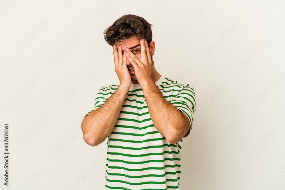 Young caucasian man isolated on white background blink through fingers frightened and nervous. Young caucasian man isolated on white background blink through fingers frightened and nervous.