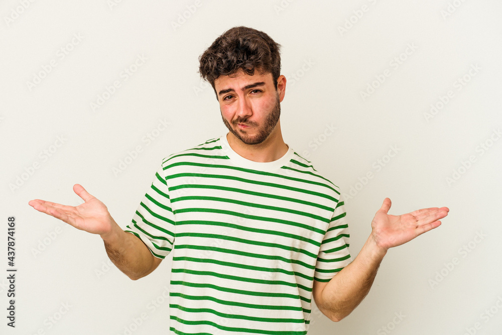 Young caucasian man isolated on white background doubting and shrugging shoulders in questioning gesture.