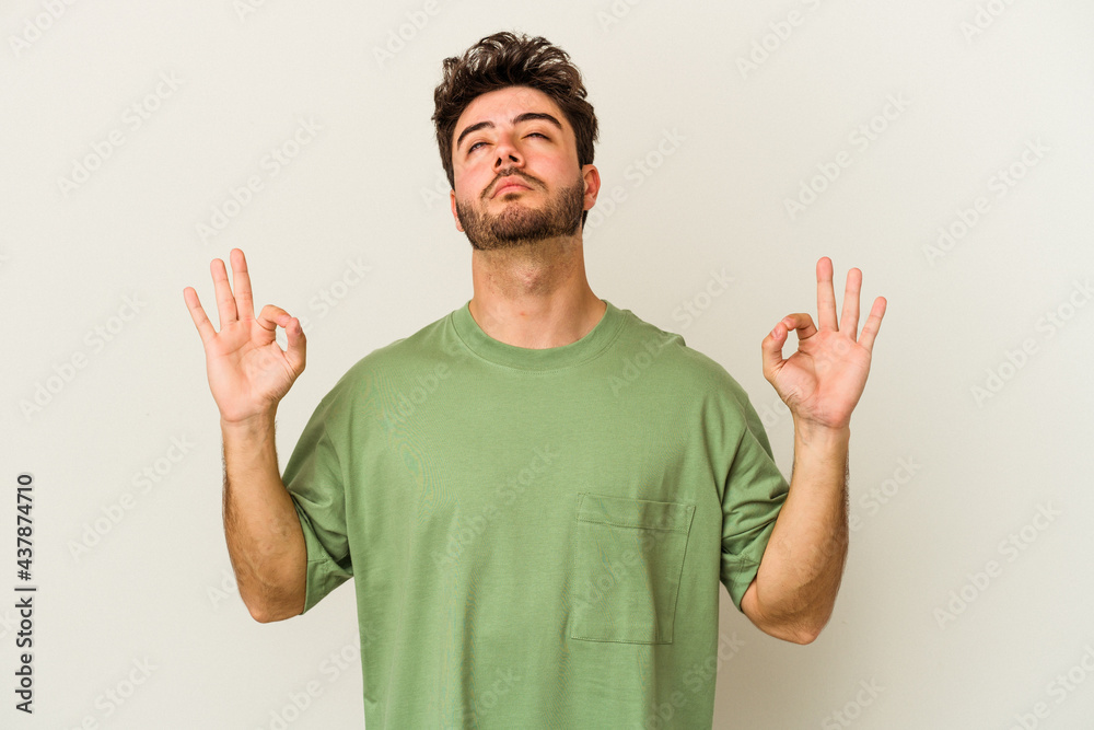 Young caucasian man isolated on white background relaxes after hard working day, she is performing yoga.