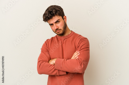 Young caucasian man isolated on white background frowning face in displeasure, keeps arms folded. © Asier