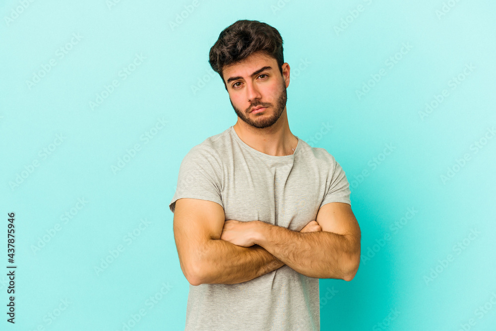 Young caucasian man isolated on blue background suspicious, uncertain, examining you. Young caucasian man isolated on blue background suspicious, uncertain, examining you.
