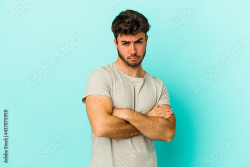Foto Young caucasian man isolated on blue background tired of a repetitive task