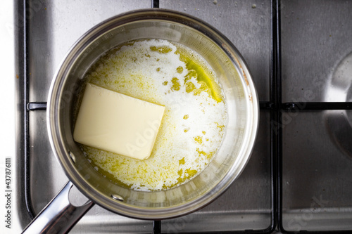 Roztapiające się masło w stalowym garnku. Gotowanie w kuchni.