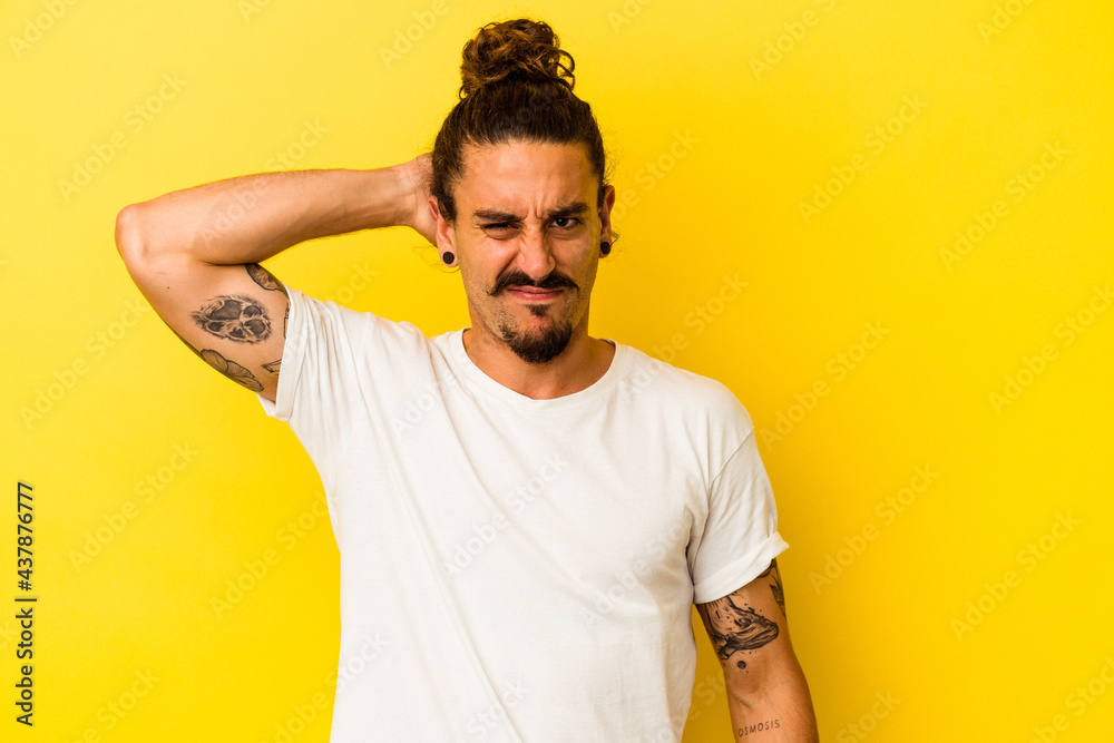 Young caucasian man with long hair isolated on yellow background suffering neck pain due to sedentary lifestyle. Young caucasian man with long hair isolated on yellow background suffering neck pain due to sedentary lifestyle.