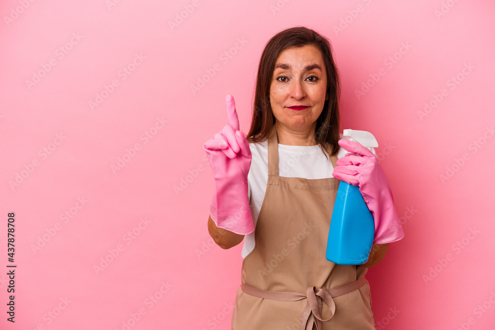 Middle age caucasian woman cleaning home isolated on pink background showing number one with finger. Middle age caucasian woman cleaning home isolated on pink background showing number one with finger.