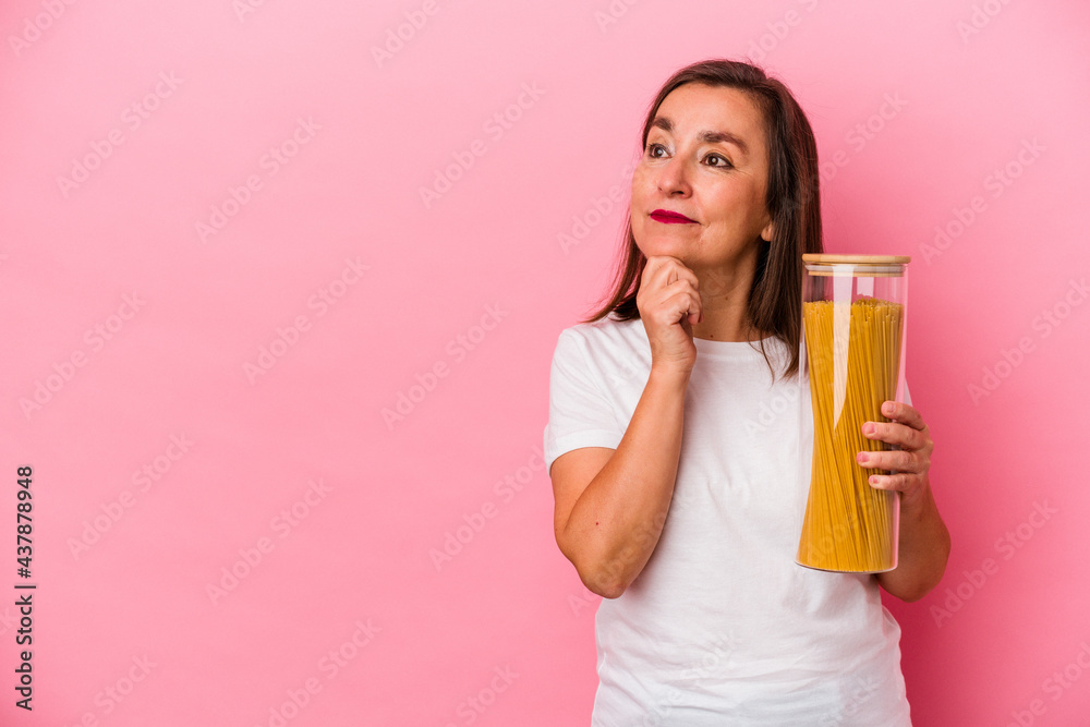 Middle age caucasian woman holding a pasta jar isolated on pink background looking sideways with doubtful and skeptical expression. Middle age caucasian woman holding a pasta jar isolated on pink background looking sideways with doubtful and skeptical expression.