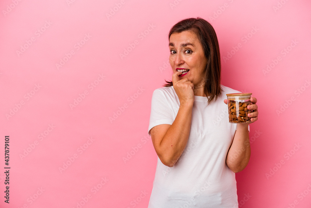 Middle age caucasian woman holding an almond jar isolated on pink background relaxed thinking about something looking at a copy space. Middle age caucasian woman holding an almond jar isolated on pink background relaxed thinking about something looking at a copy space.