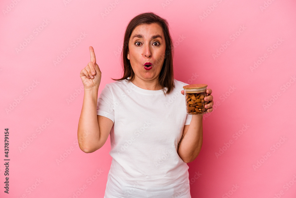 Middle age caucasian woman holding an almond jar isolated on pink background having some great idea, concept of creativity. Middle age caucasian woman holding an almond jar isolated on pink background having some great idea, concept of creativity.