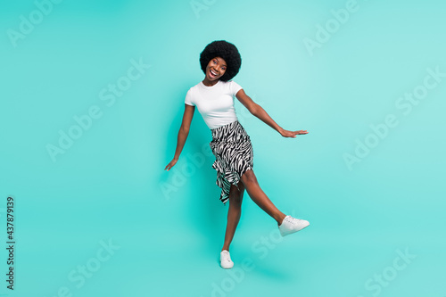 Fototapeta Naklejka Na Ścianę i Meble -  Photo of cute funky dark skin woman dressed casual outfit smiling waking isolated turquoise color background