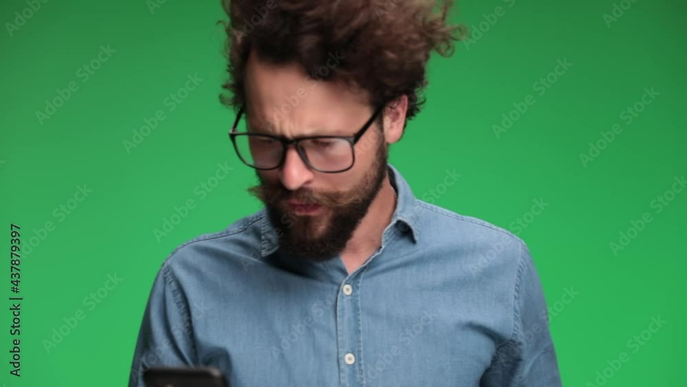 young casual man putting his glasses on, looking at his phone and feeling shocked then angry, arguing and swearing, being aggressive young casual man putting his glasses on, looking at his phone and feeling shocked then angry, arguing and swearing, being aggressive