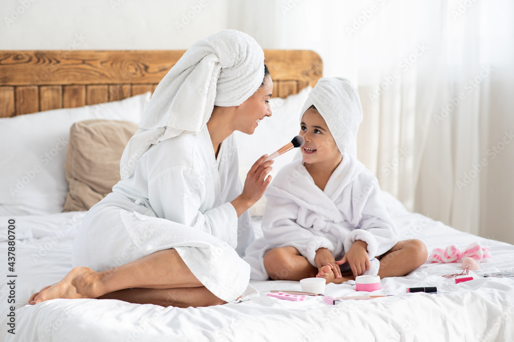 Young mother touching her cute daughter nose with brush Young mother touching her cute daughter nose with brush