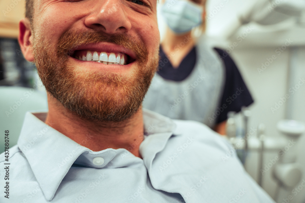 Caucasian male client smiling wide with new shiny teeth after visiting the orthodontist Caucasian male client smiling wide with new shiny teeth after visiting the orthodontist