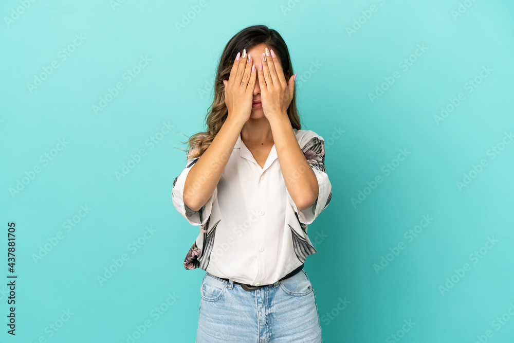 Young woman over isolated blue background covering eyes by hands Young woman over isolated blue background covering eyes by hands