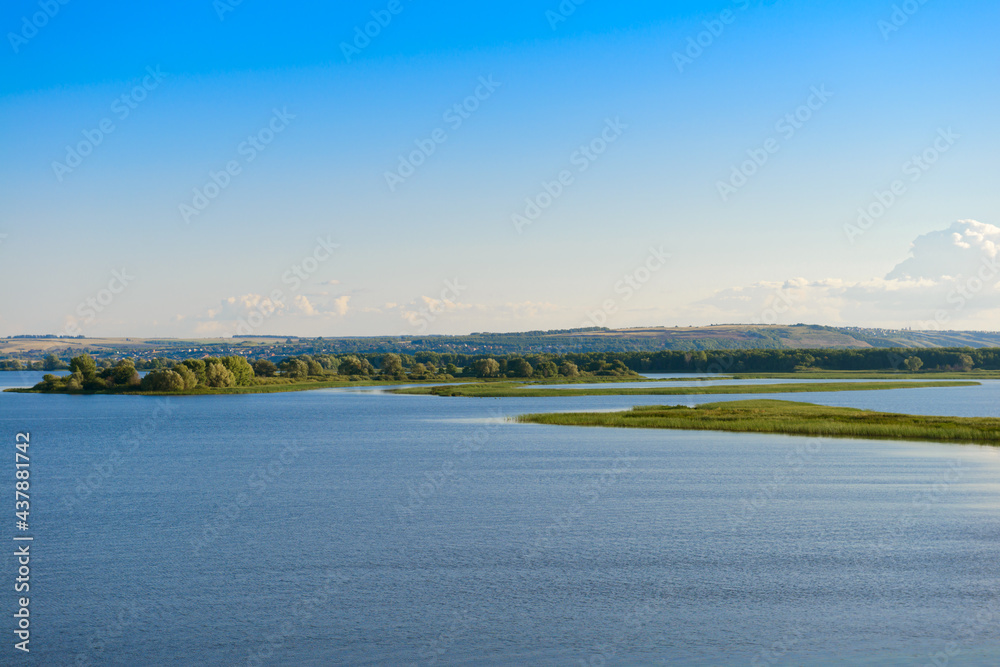 Summer landscape with a wide river, islands, and blue sky