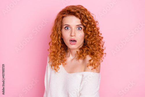 Photo portrait of red haired curly woman staring amazed with opened mouth isolated on pastel pink color background