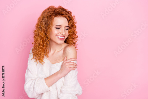 Photo portrait of red haired curly woman smiling dreamy wearing sweater with off-shoulder isolated on pastel pink color background