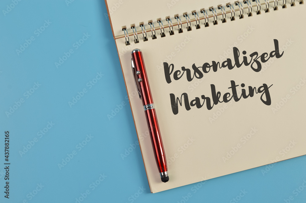 Top view of pen and notebook written with PERSONALIZED MARKETING Top view of pen and notebook written with PERSONALIZED MARKETING
