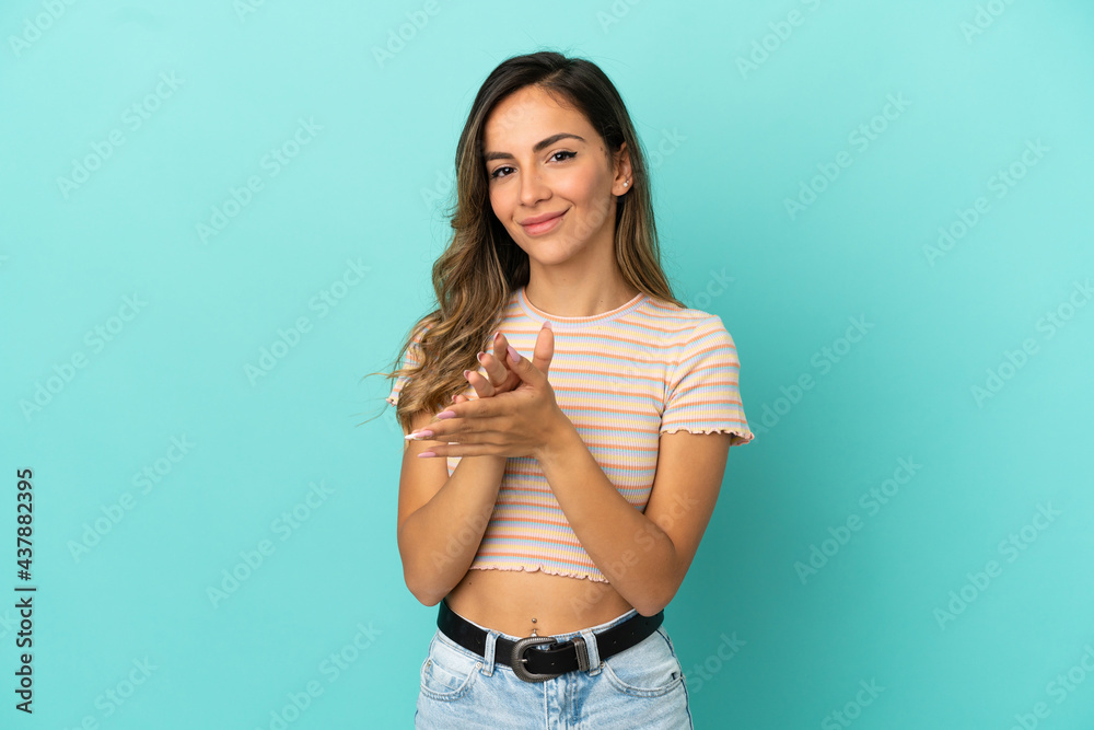 Young woman over isolated blue background applauding after presentation in a conference Young woman over isolated blue background applauding after presentation in a conference