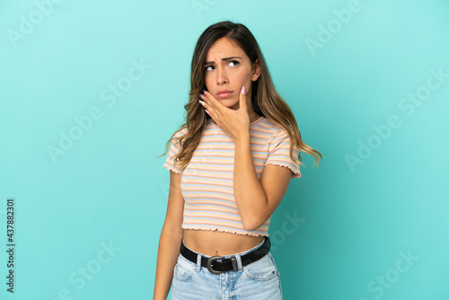 Young woman over isolated blue background having doubts and with confuse face expression © luismolinero