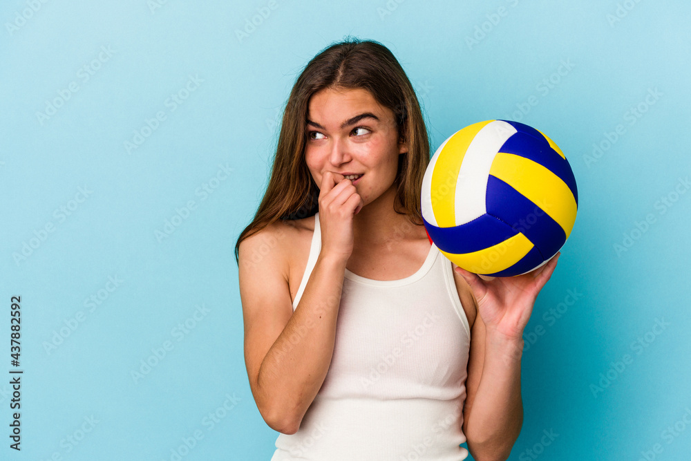Young caucasian woman playing volleyball isolated on blue background relaxed thinking about something looking at a copy space.