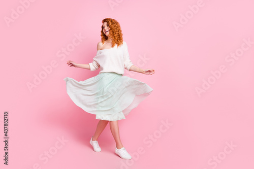 Full length body size photo of with red hair woman going forward looking copyspace smiling isolated on pastel pink color background