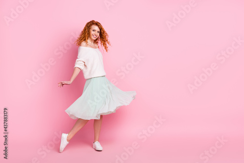 Photo portrait of young girl smiling spinning in skirt dancing on holidays isolated pastel pink color background