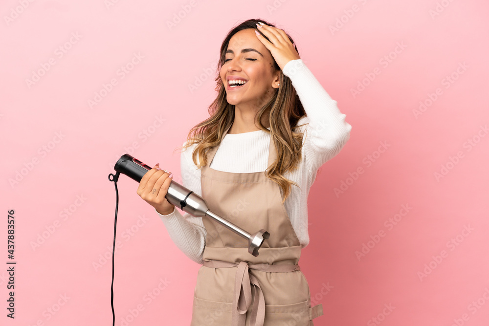 Young woman using hand blender over isolated pink background smiling a lot Young woman using hand blender over isolated pink background smiling a lot