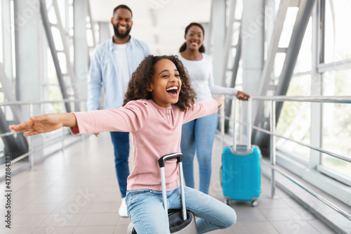 Happy black family traveling with kid, standing in airport