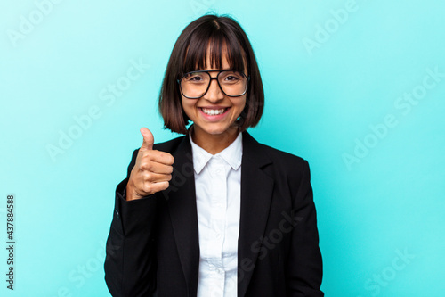 Young business mixed race woman isolated on blue background smiling and raising thumb up