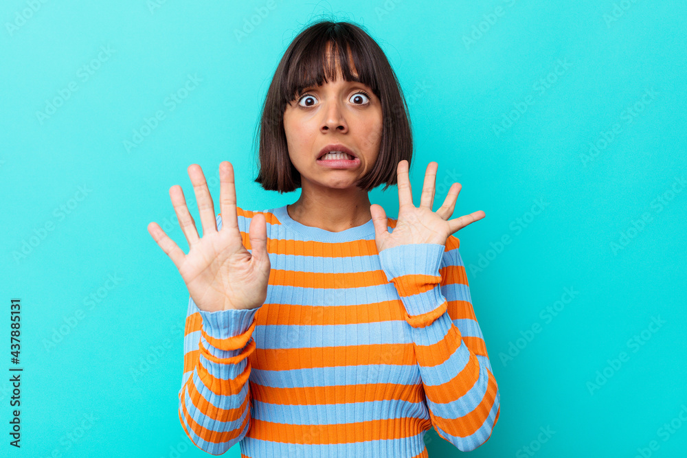 Young mixed race woman isolated on blue background rejecting someone showing a gesture of disgust. Young mixed race woman isolated on blue background rejecting someone showing a gesture of disgust.