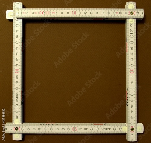 The folding ruler is folded in a square on a brown background