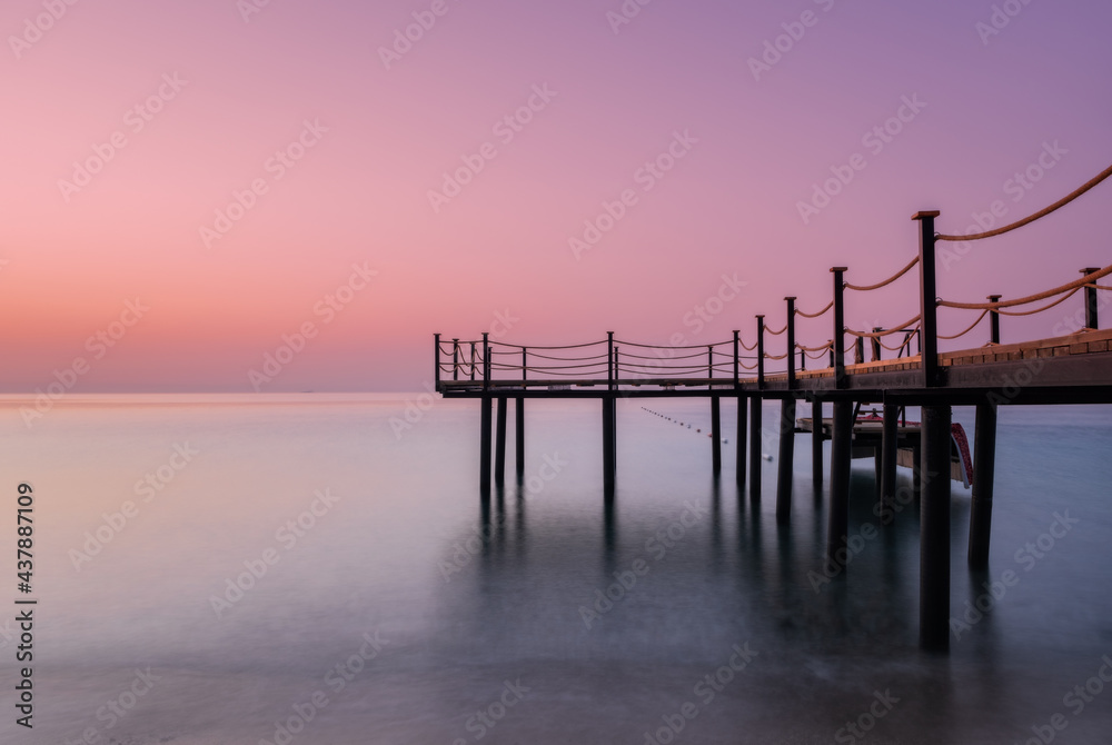 Pier on the sea at sunrise with long exposure and beautiful colors. Tekirova, Kemer, Turkey. May 2021