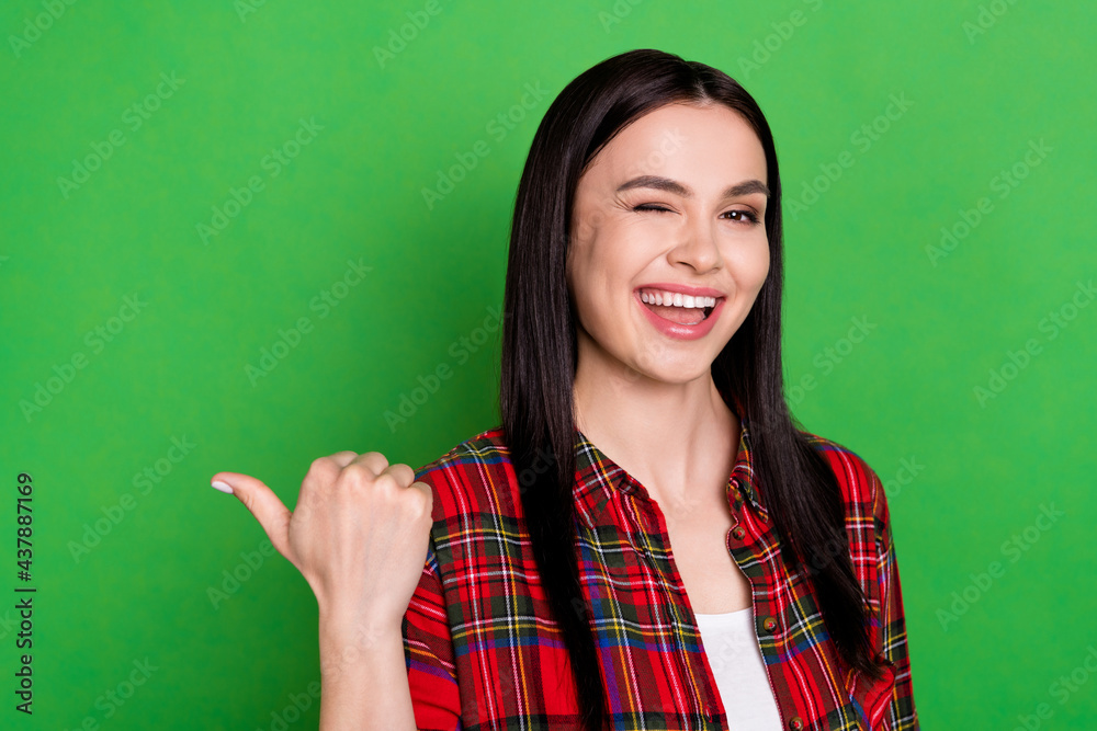 Photo of sweet millennial lady point empty space blink wear red shirt isolated on green color background Photo of sweet millennial lady point empty space blink wear red shirt isolated on green color background