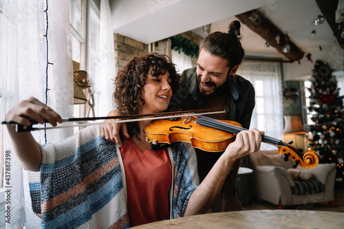 Private male music teacher giving violin lessons to a woman at home © NDABCREATIVITY