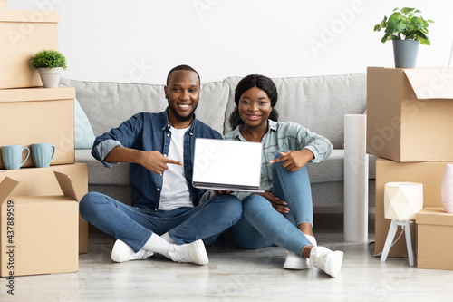 Black Spouses Pointing At Laptop With Blank Screen At Their New Home